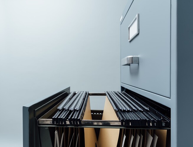 A filing cabinet with an open drawer. The drawer is full of hanging files, symbolising storage and organisation