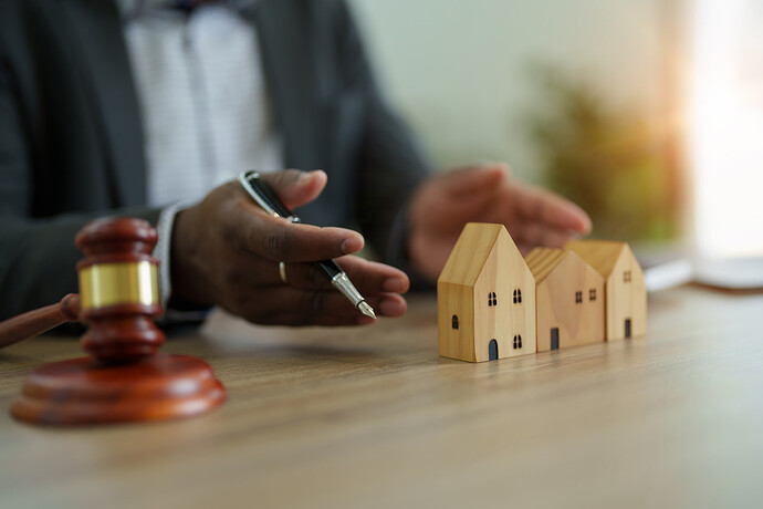 Hands surrounding wooden houses with a gavel on the desk