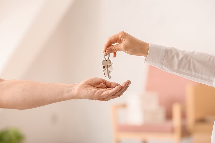A person holding their hand out to receive a set of house keys